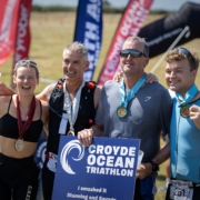 Winners at the finish line holding a sign up saying Croyde Ocean Triathlon