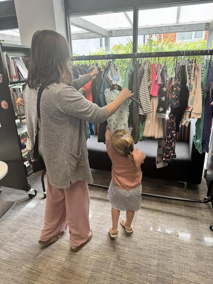 Mum and child browsing a rail of clothes at a clothes swap